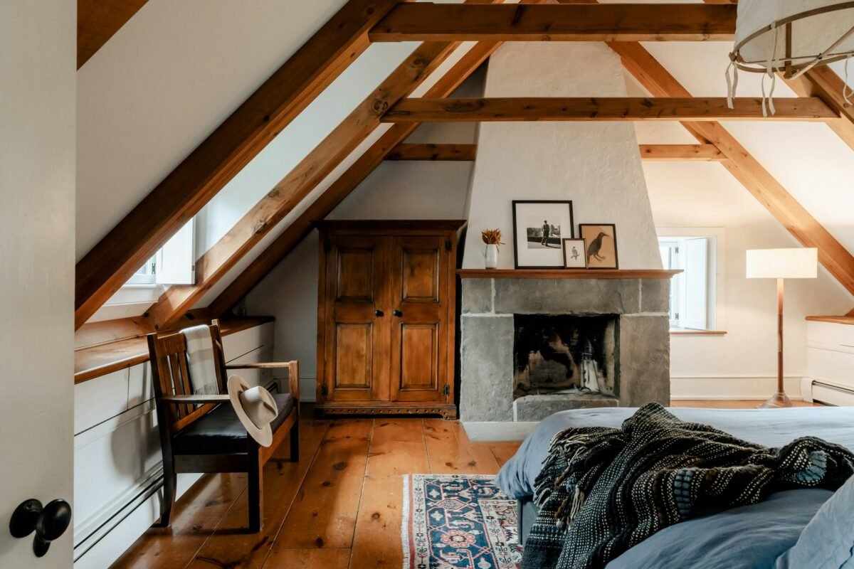 Loft bedroom with wooden beams, a cosy bed and a fireplace