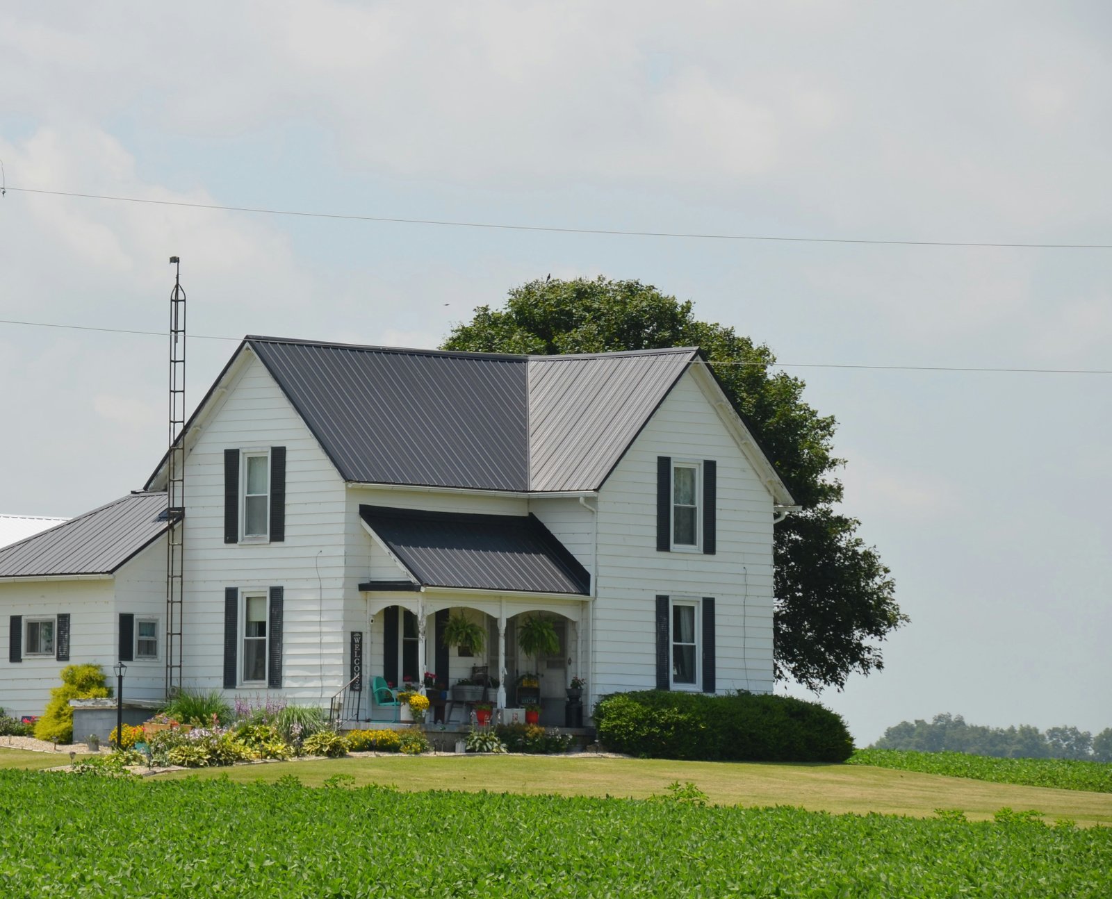 Two-storey frame farmhouse with a porch among green fields